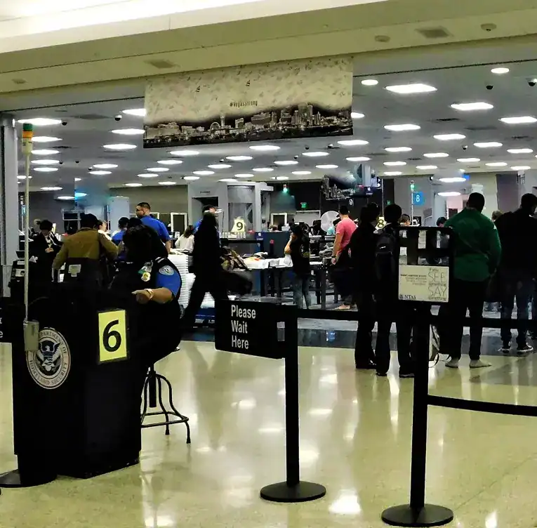 Pasajeros en el aeropuerto con personal de inmigración y control de seguridad, escenario común para migrantes en tránsito en una terminal aérea internacional. – SoyMigrante.com REVISTA