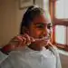 Niña sonriendo mientras se cepilla los dientes, promoviendo salud bucal y bienestar infantil. Imagen relacionada con cuidados personales y educación en higiene para niños.