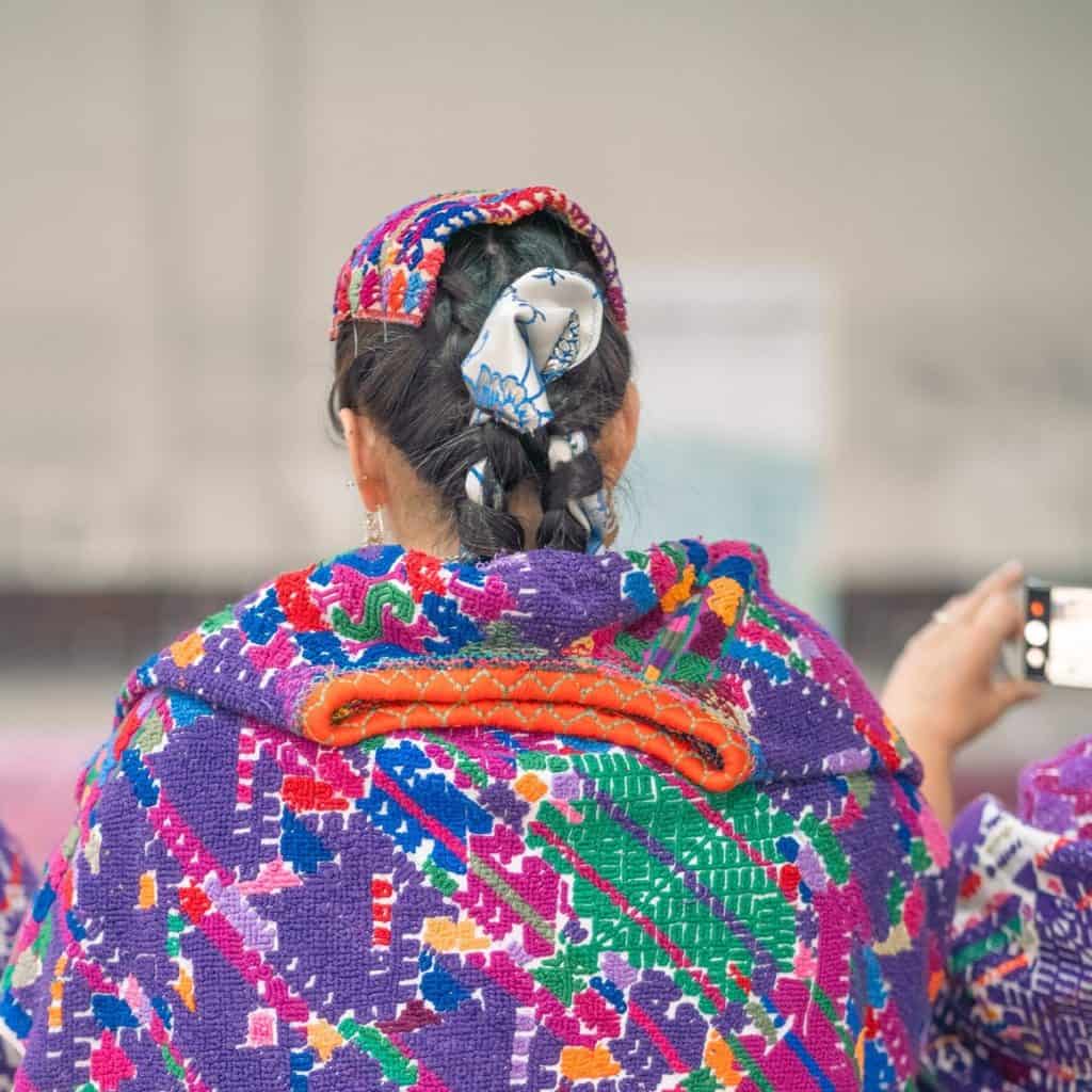 Colaboradora con vestimenta tradicional y cabello adornado con accesorios coloridos en una actividad cultural mexicana.