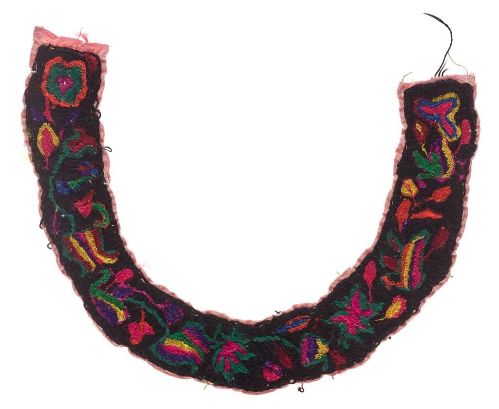 Colorido collar bordado tradicional mexicano, con flores y patrones vibrantes en fondo negro, representando cultura y artesanía indígena. – SoyMigrante.com REVISTA