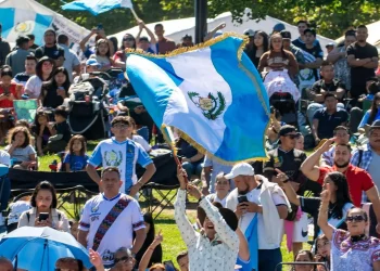 Banderas y símbolos de Guatemala en una celebración cultural llena de inmigrantes y comunidad en un parque, promoviendo la identidad y orgullo guatemalteco.
