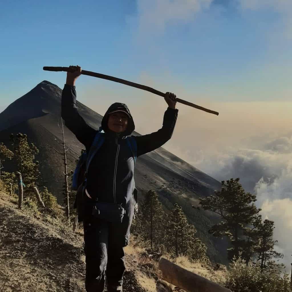 Joven excursionista en la montaña con mochila y bastón en un paisaje volcánico. – SoyMigrante.com REVISTA
