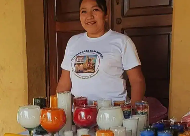 Exposición de velas artesanales en un puesto de mercado, mostrando la variedad de colores y diseños, en un contexto de comunidad migrante en México.