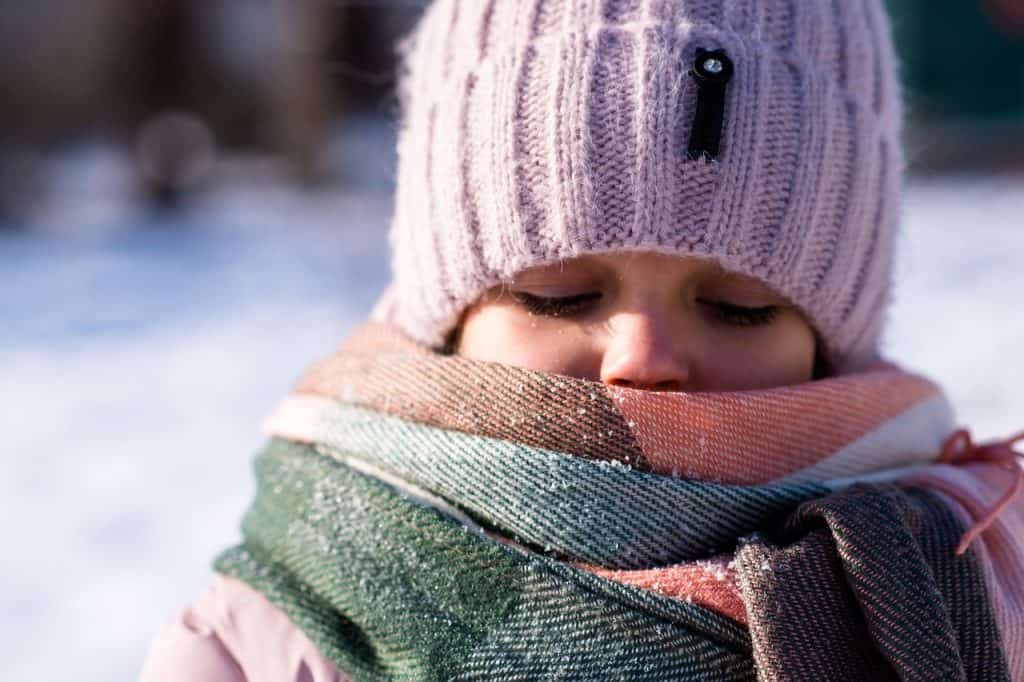 Pelea de la niña con bufanda y gorro de invierno, sobre fondo de nieve, en clima frío, transporte internacional, comunidad migrante, vida en el extranjero, historias de migrantes, revisa la revista SoyMigrante.com REVISTA.