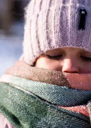 Pelea de la niña con bufanda y gorro de invierno, sobre fondo de nieve, en clima frío, transporte internacional, comunidad migrante, vida en el extranjero, historias de migrantes, revisa la revista SoyMigrante.com REVISTA. – SoyMigrante.com REVISTA