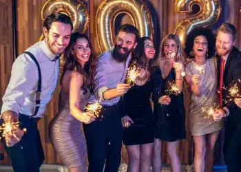 Celebrities celebrando con bengalas en una fiesta de fin de año 2022, decorada con globos dorados en forma de números 2023, mostrando alegría y unión en la celebración.