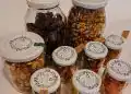 Jarras de frutos secos y snacks caseros en envases reutilizables, ideales para alimentación saludable y sostenible, con etiquetas personalizadas en el estilo de SoyMigrante.com REVISTA. – SoyMigrante.com REVISTA