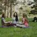 Meditación en grupo de mujeres en un parque, practicando yoga y mindfulness, promoviendo bienestar, salud mental y conexión con la naturaleza. Concepto de relajación y equilibrio emocional.