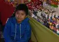 Puesto de venta de figuritas navideñas y decoraciones tradicionales en un mercado mexicano, con niño sonriendo en primer plano y colores festivos. – SoyMigrante.com REVISTA