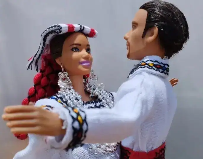 Diversidad cultural en celebración, figura de muñecos de pareja con trajes tradicionales, representación artística de migrantes en la Revista SoyMigrante, enfatizando la integración y cultura latinoamericana.