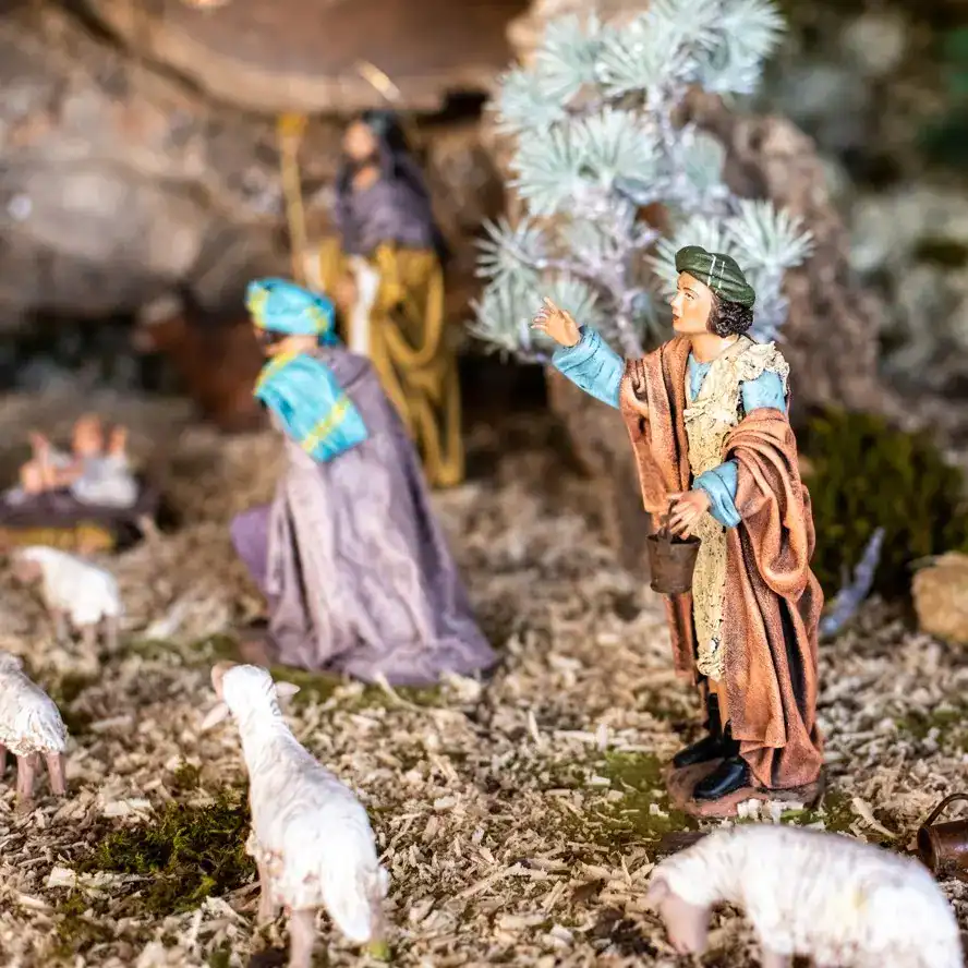 Pastor o figura religiosa en un nacimiento navideño artesanal, con ovejas y detalles naturales en el entorno, representando la tradición cultural y religiosa en la celebración navideña en México. – SoyMigrante.com REVISTA