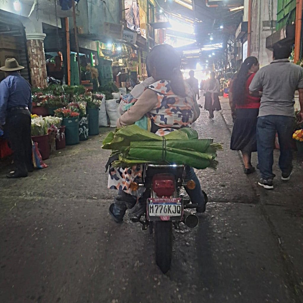 Cerca de migrantes en un mercado de calle en Ciudad de México, vendiendo flores y productos en una escena urbana, representando la vida diaria y el trabajo de la comunidad migrante.