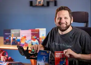 Libro "En una silla de morfeo" del autor Alan Terenbaum, mostrando diversidad e inclusión en la literatura, con decoraciones coloridas y fondos de libros en una sala acogedora.