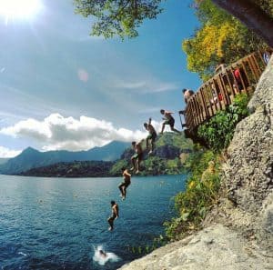 Saltando del muelle en el lago de Atitlán con un grupo de amigos durante un día soleado en Guatemala.