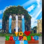Puerta histórica de San Pablo en Guatemala, decorada con telas azules y un cartel colorido que dice "Yo amo San Pablo", destacando la belleza cultural y turística de este destino. – SoyMigrante.com REVISTA