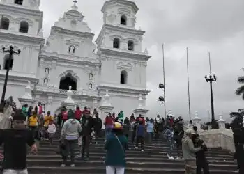 Imponente iglesia colonial blanca en el centro de la ciudad con multitud de visitantes en la escalinata.
