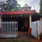Casa tradicional con barbacoa en el patio, en un día soleado, decorada con banderines de colores, en un entorno rural tranquilo, perfecta para eventos comunitarios y celebraciones familiares. – SoyMigrante.com REVISTA