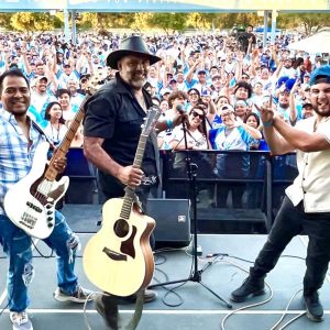 Discurso y música en celebración de inmigrantes en una multitud en un evento cultural y social.
