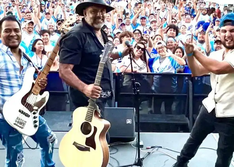 Discurso y música en celebración de inmigrantes en una multitud en un evento cultural y social.