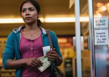 Dinámica mujer migrante en un cajero automático con billetes y recibo, en un entorno urbano, promoviendo servicios financieros para inmigrantes y resaltando temas de remesas y transferencia de dinero en América Latina.