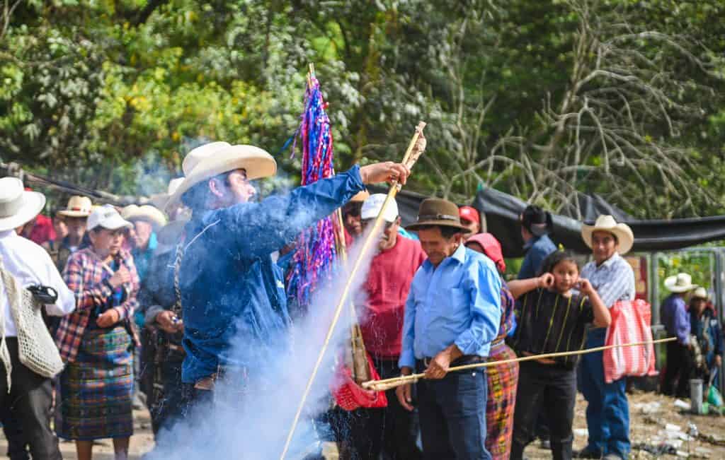 Celebración cultural en el Día de los Muertos con miembros de la comunidad indígena, vestimenta tradicional y ofrendas en un entorno natural en Guatemala. – SoyMigrante.com REVISTA