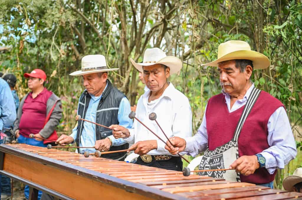 Gente tocando marimba tradicional en un entorno natural, representando la cultura y raíces indígenas en México. – SoyMigrante.com REVISTA