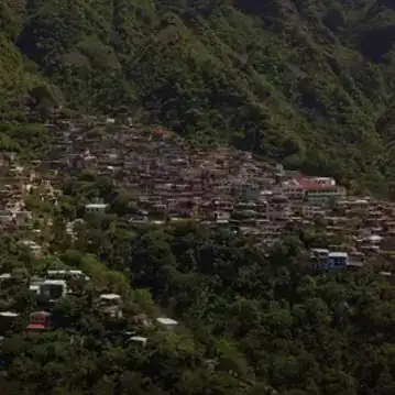 Cabañas y casas en las montañas de una comunidad rural en México, rodeadas de naturaleza exuberante y árboles verdes densos. – SoyMigrante.com REVISTA
