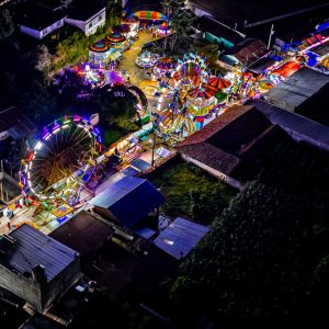 Luces y atracciones en feria nocturna en un parque lleno de luces de neón y carruseles, ambiente festivo y colorido en una celebración tradicional en México. – SoyMigrante.com REVISTA