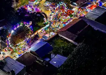 Luces y atracciones en feria nocturna en un parque lleno de luces de neón y carruseles, ambiente festivo y colorido en una celebración tradicional en México.