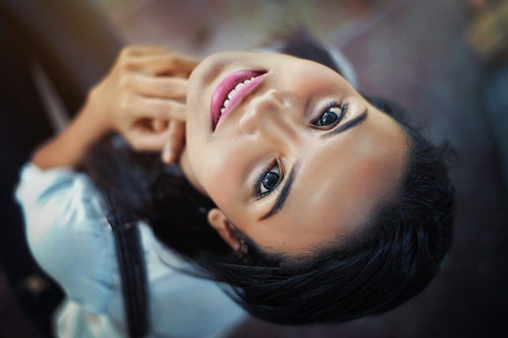 Vendedora de belleza con piel radiante, maquillaje profesional, rostro joven y sonrisa encantadora, imagen de moda y cuidado personal para revista SoyMigrante.com REVISTA.