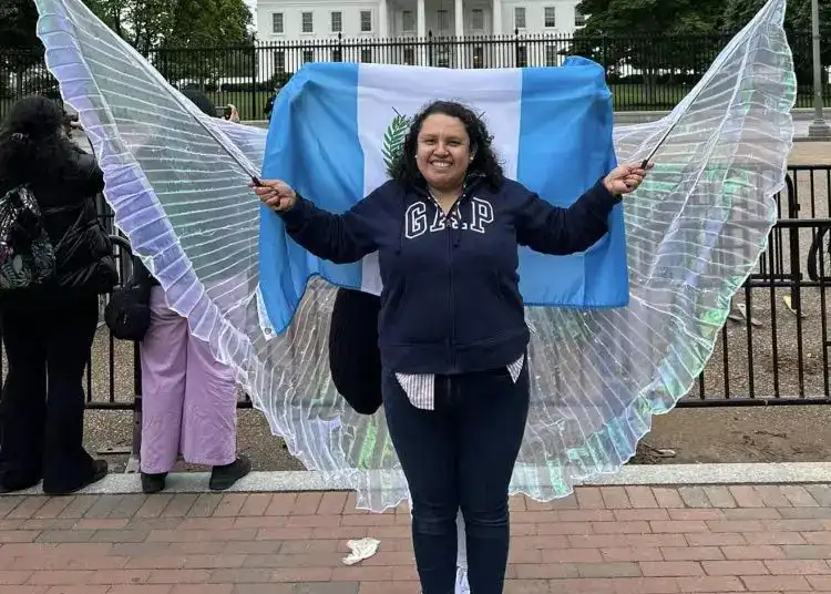 Vendedora con alas de mariposa en protesta frente a la Casa Blanca, representando la comunidad migrante en Estados Unidos. Imagen de activismo y derechos migratorios.