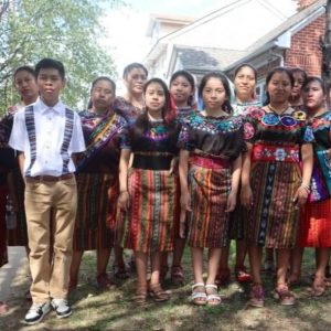 Jóvenes con traje típico indígena en un evento cultural en un ambiente urbano, destacando la identidad y tradición mexicana, promoviendo orgullo cultural y diversidad en la comunidad.