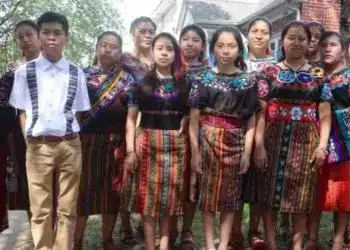 Jóvenes con traje típico indígena en un evento cultural en un ambiente urbano, destacando la identidad y tradición mexicana, promoviendo orgullo cultural y diversidad en la comunidad.