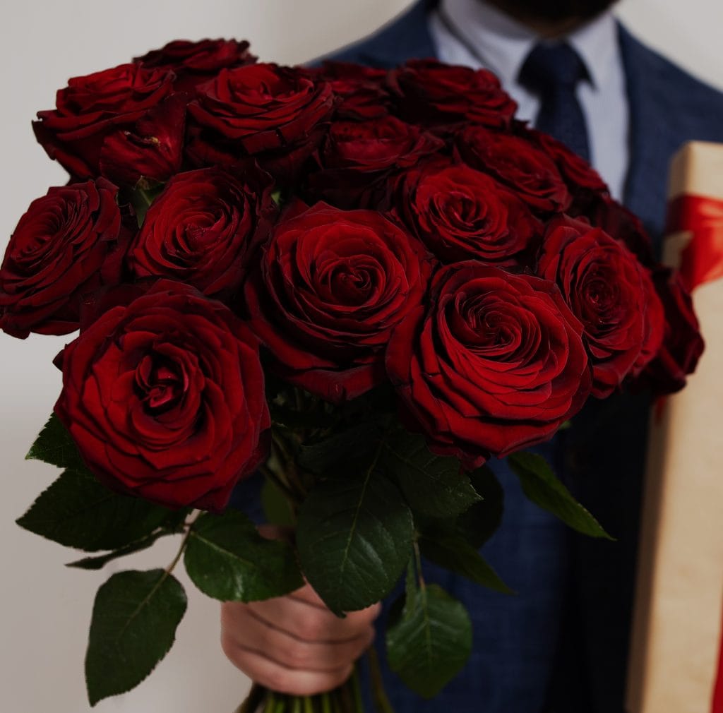 Ramo de rosas rojas en mano, símbolo de amor y celebración, ideal para ocasiones especiales y momentos románticos en la comunidad de migrantes en México y América Latina. – SoyMigrante.com REVISTA