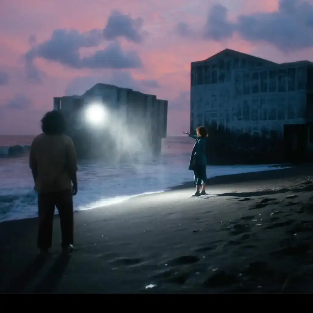 Varios niños en la playa durante el atardecer, con estructuras en el fondo y luces brillantes, en una escena que combina nostalgia y misterio, reflejando temas de migración y presencia humana en ambientes costeros. – SoyMigrante.com REVISTA