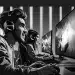 Jugadores de videojuegos en una competencia de eSports con auriculares y monitores grandes, en un entorno moderno y competitivo. – SoyMigrante.com REVISTA