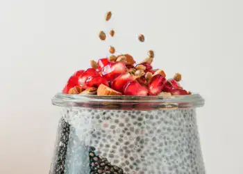 Chía y fruta con granada en un tarro de vidrio, alimentación saludable, superalimentos, desayuno nutritivo, semillas de chía y fruta fresca, tendencia en dietas Wellness y alimentación consciente.