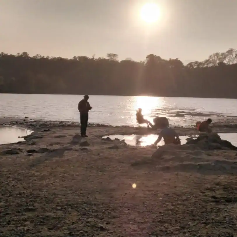 Pescadores y migrantes disfrutando del atardecer en un río, reflejando la vida y cultura de los migrantes en comunidades rurales. – SoyMigrante.com REVISTA