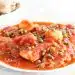 Deliciosa pasta con salsa de tomate y carne, presentada en un plato blanco, resaltando sabores tradicionales italianos.