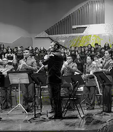 Recreacion del estreno del Himno Nacional de Guatemala en el Conservatorio de Música – SoyMigrante.com REVISTA Una orquesta con director y músicos en un escenario durante un concierto.