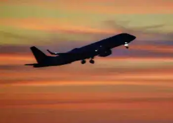 Vuelo de avión en atardecer con cielo colorido, símbolo de migración y viajes internacionales.