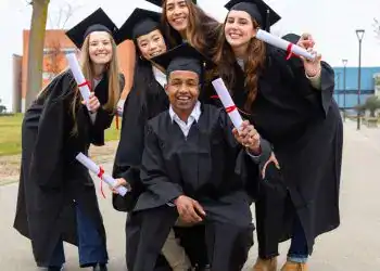 Graduados universitarios celebrando logro académico, con toga y birrete, en un evento de graduación, mostrando diversidad y éxito en la educación.