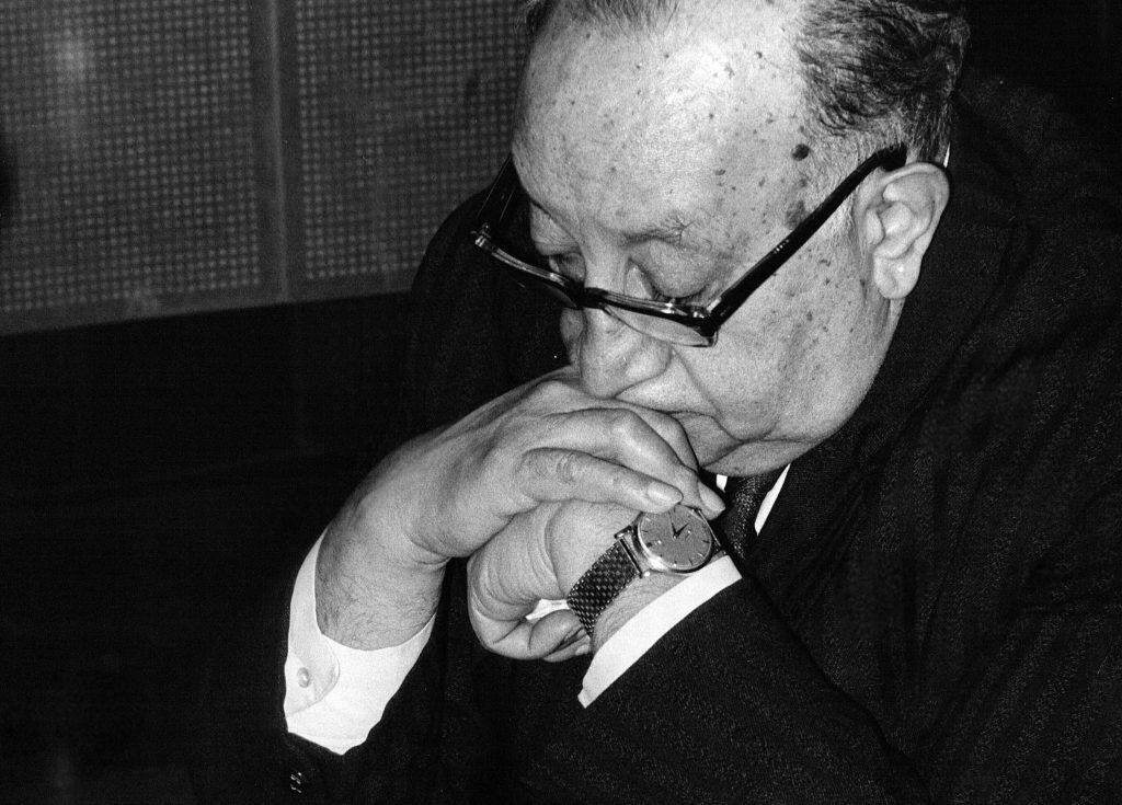 Filtrado: Retrato en negro y blanco de un hombre mayor con gafas, con las manos juntas y la cabeza inclinada, en actitud reflexiva. – SoyMigrante.com REVISTA