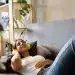Disfrutando de música y relajación en un ambiente acogedor, mujer joven escucha con auriculares amarillos, ilustrando el bienestar y la cultura migrante en la vida cotidiana en el marco de SoyMigrante.com REVISTA.