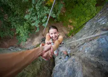 Aventurera jovenes escalando una roca en un árbol en un bosque, practicando turismo de aventura y deportes en plena naturaleza. – SoyMigrante.com REVISTA