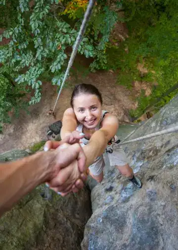 Superar el miedo: consejos prácticos para afrontar momentos difíciles – SoyMigrante.com REVISTA Aventurera jovenes escalando una roca en un árbol en un bosque, practicando turismo de aventura y deportes en plena naturaleza. – SoyMigrante.com REVISTA