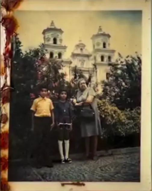Fotografía del álbum familiar. Amalia, en el centro, junto a su abuelita Mélida, durante una visita a la basílica del Cristo de Esquipulas, en Chiquimula. Amalia llama a su abuelita "Mi estrella del Norte", por todos los consejos que recibió de ella y que siguen siendo su guía e inspiración. – SoyMigrante.com REVISTA Fotografía del álbum familiar. Amalia, en el centro, junto a su abuelita Mélida, durante una visita a la basílica del Cristo de Esquipulas, en Chiquimula. Amalia llama a su abuelita "Mi estrella del Norte", por todos los consejos que recibió de ella y que siguen siendo su guía e inspiración. – SoyMigrante.com REVISTA
