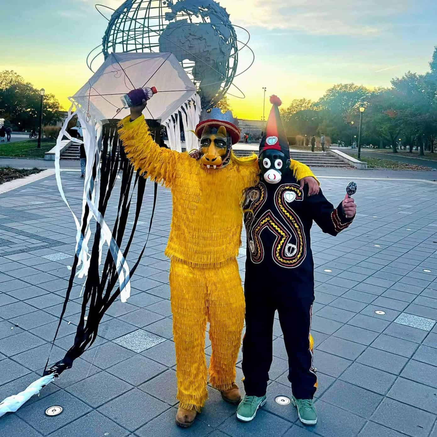 Hombre disfrazado de jaguar y otro con máscara de payaso en celebración tradicional mexicana en una plaza pública al atardecer. Personas y espacios abiertos en el fondo, ambiente festivo y cultural.