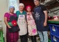 Recetas tradicionales mexicanas preparadas por migrantes en un ambiente de cocina comunitaria, resaltando la cultura, unión y el trabajo en equipo. – SoyMigrante.com REVISTA