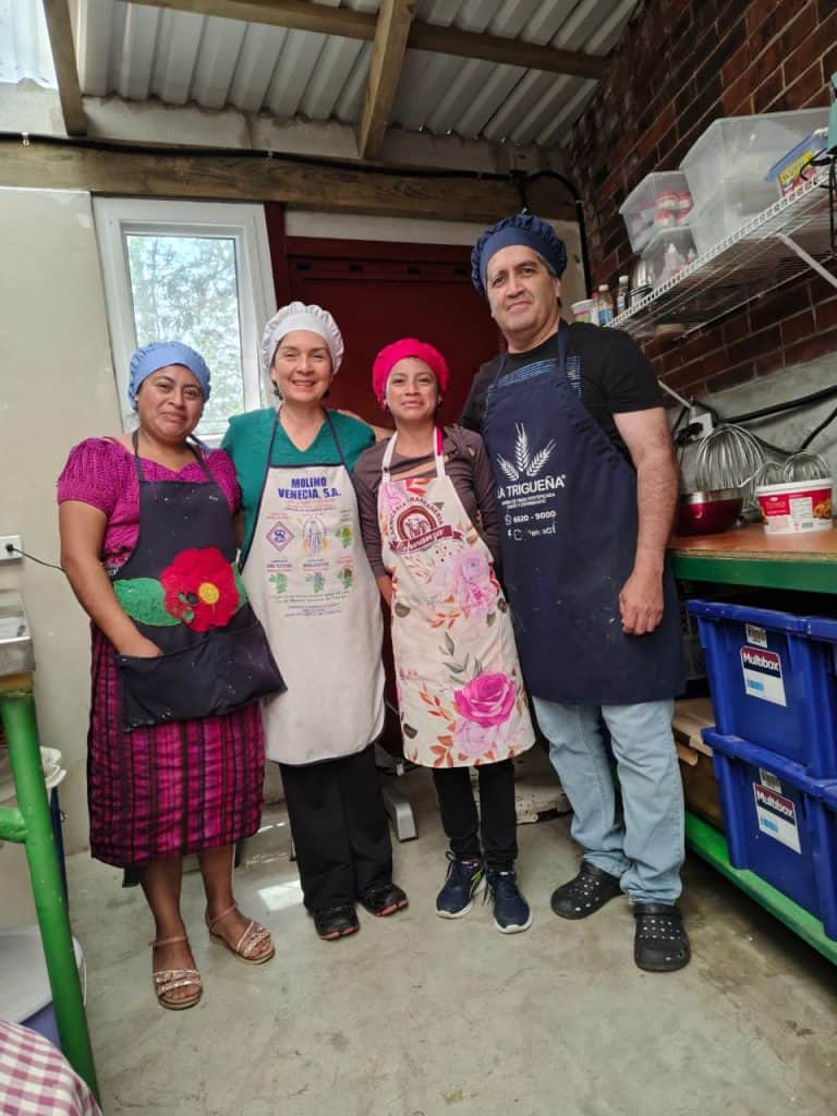 Recetas tradicionales mexicanas preparadas por migrantes en un ambiente de cocina comunitaria, resaltando la cultura, unión y el trabajo en equipo. – SoyMigrante.com REVISTA